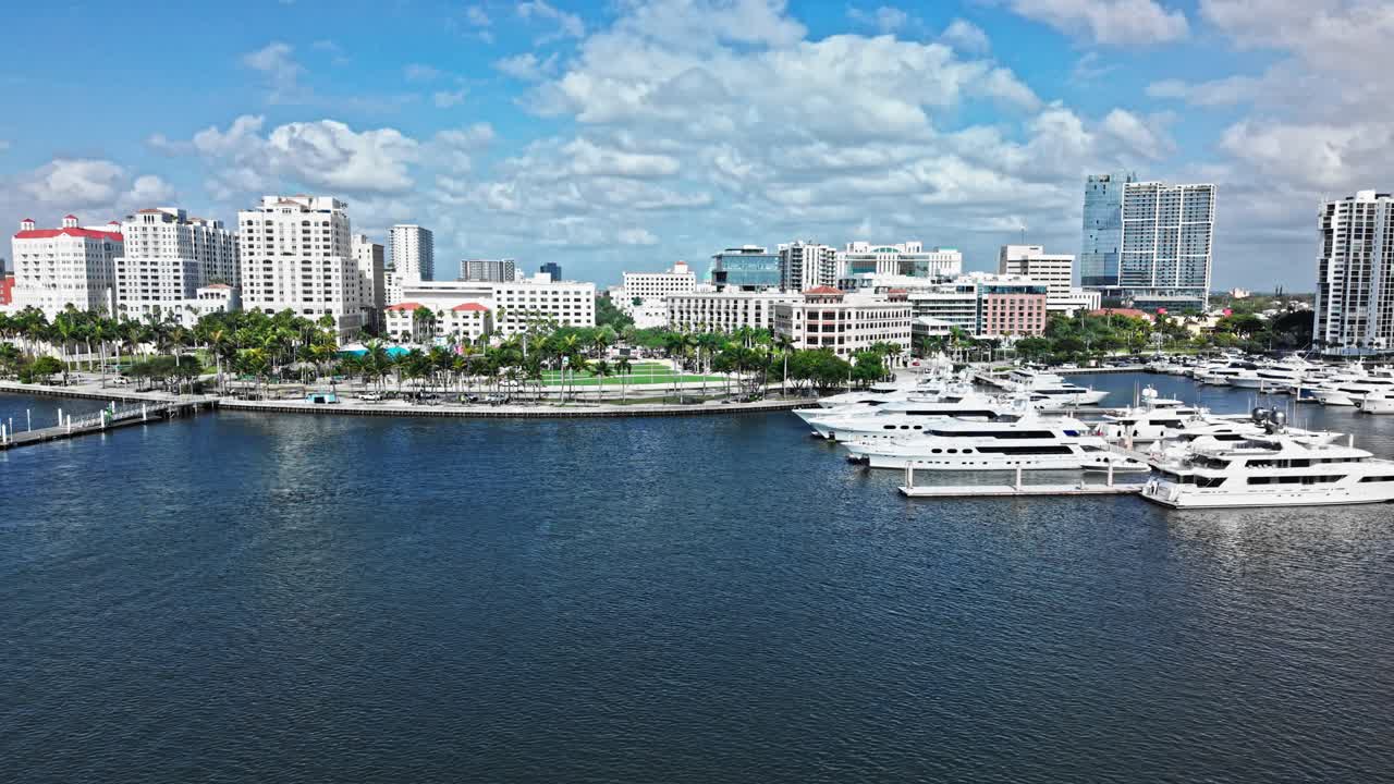 Pan drone shot of West Palm Beach marina, harbor and cityscape with white yachts during the day in Florida, USA