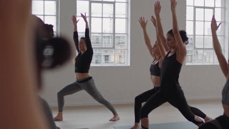 yoga-class-group-of-multiracial-women-practicing-warrior-pose-enjoying-healthy-lifestyle-exercising-in-fitness-studio-instructor-teaching-group-meditation-at-sunrise