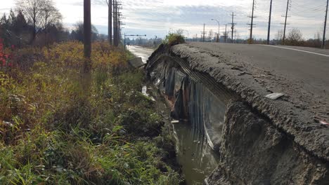 Damaged-road-from-water-flowing-underneath-in-a-flood-at-Abbotsford,-BC,-Canada---dolly-shot