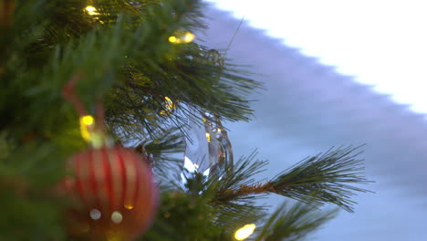 a young woman's hand hangs a glass ornament on a christmas tree