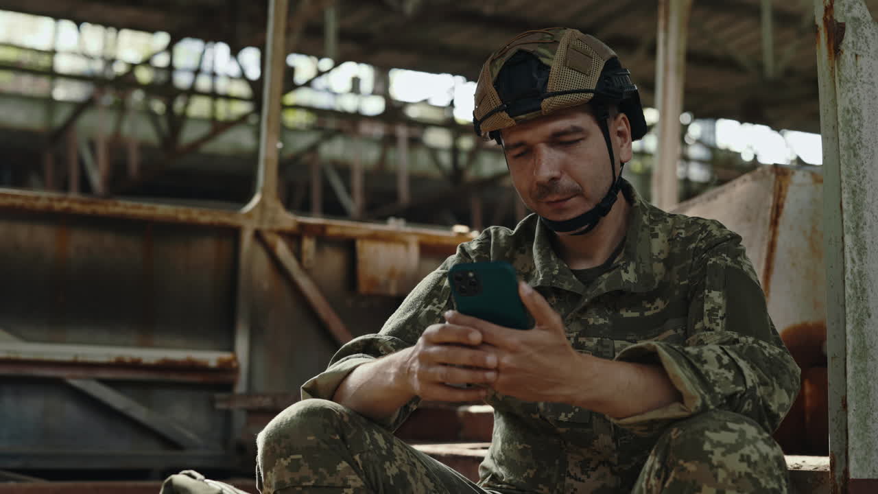Soldier using smartphone in an abandoned building