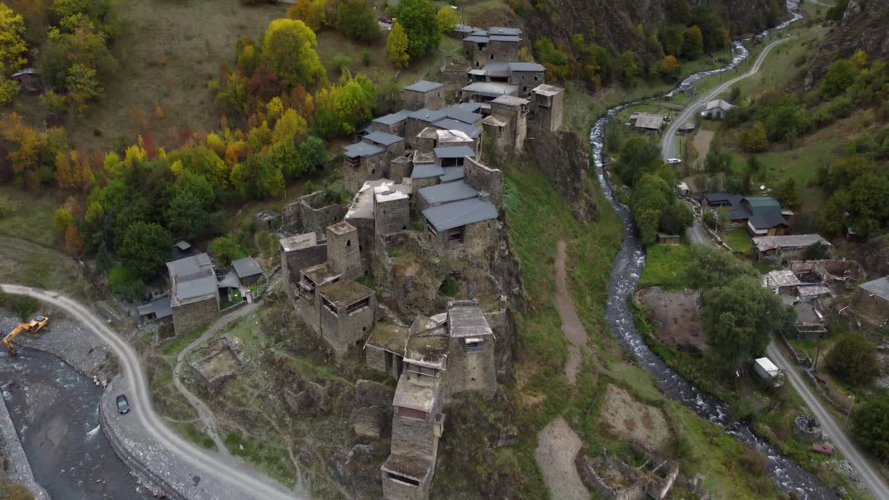 Schräger Panorama-Drohnenflug über das alte Steindorf Schatili mit kurvenreicher Straße durch den Bergpass entlang des Flusses Aragvi, Chewsuretien, Mzcheta-Mtianeti, Georgien