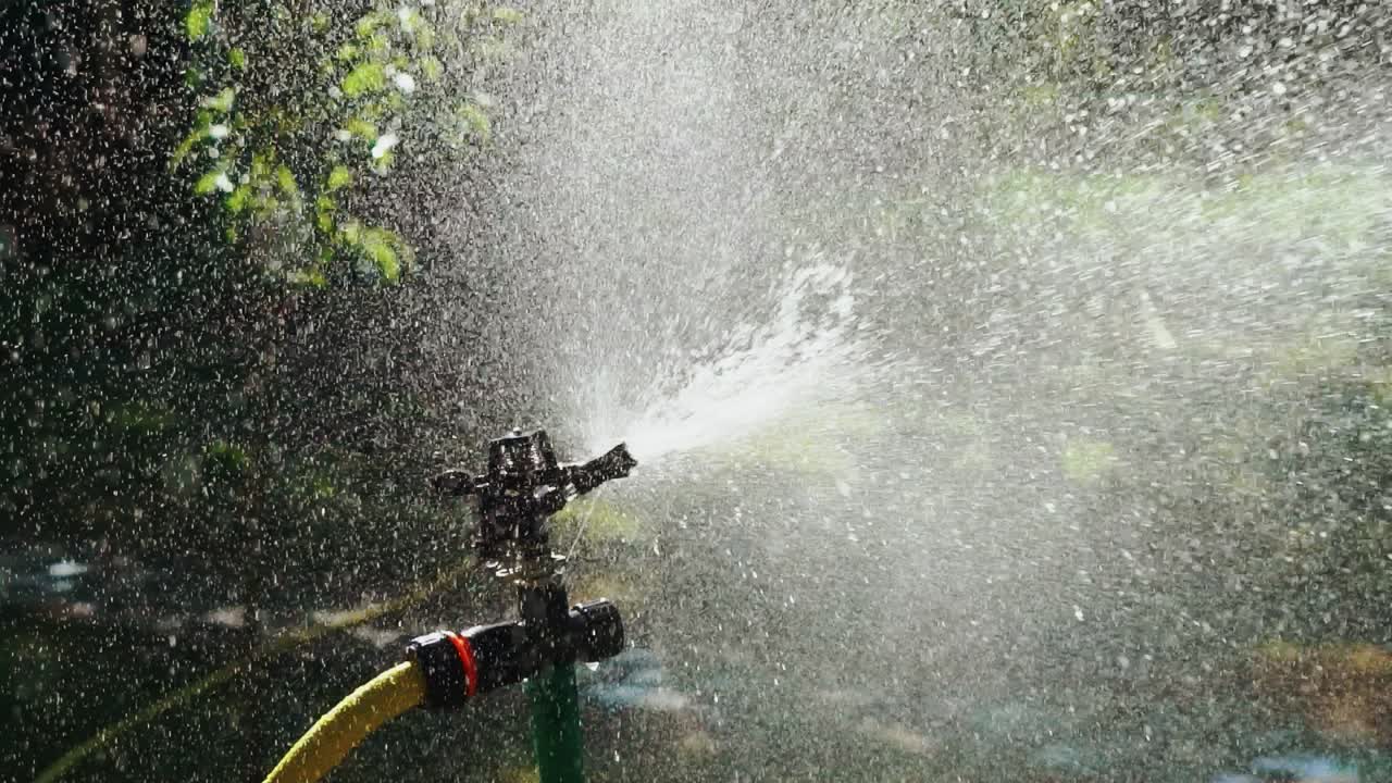 Lawn Sprinkler in Action. Watering the green grass. Slow motion