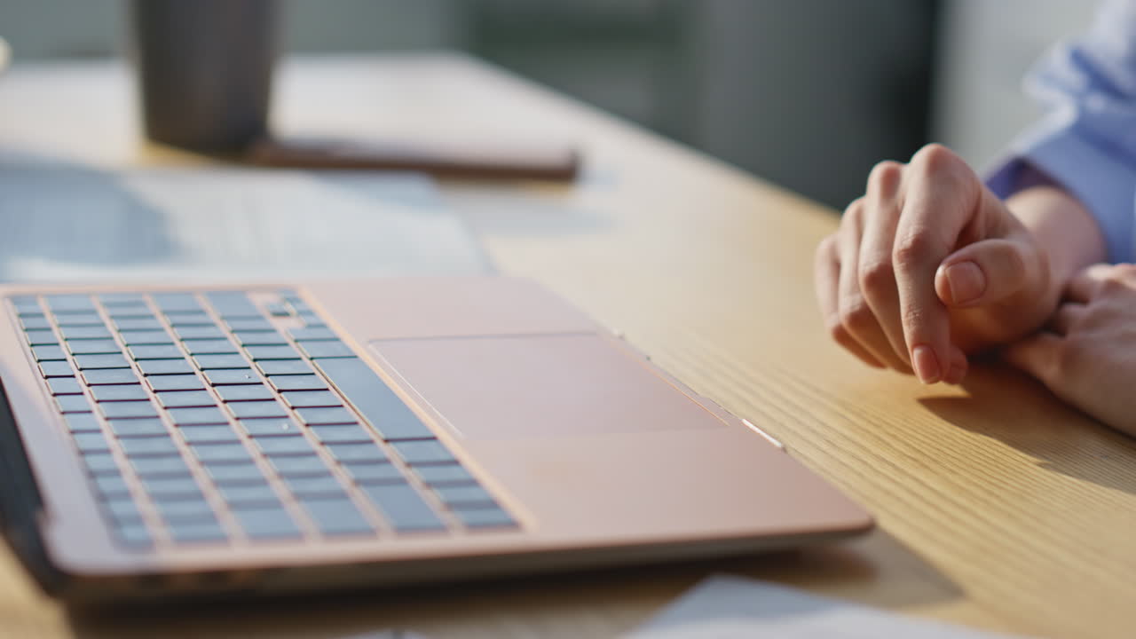 Girl hand tapping laptop touchpad browsing website at apartment table closeup