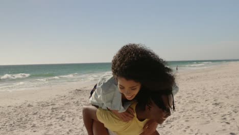 Man-giving-piggyback-ride-to-woman-on-the-beach-4k