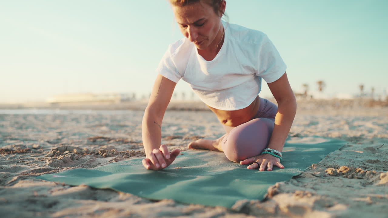 una mujer deportiva haciendo ejercicios de calentamiento en una alfombra de yoga al aire libre.