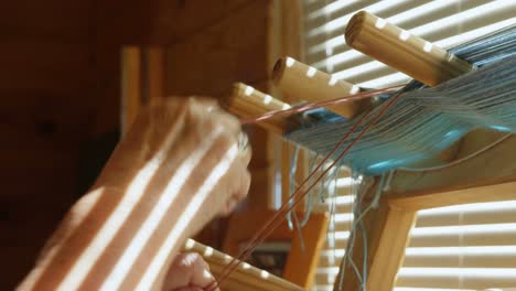 Close-up-of-old-caucasian-senior-woman-preparing-and-standing-at-hand-loom-machine-in-a-workshop-4k