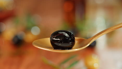 black olive on a gold spoon