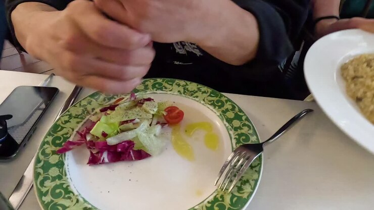 Person seasoning salad with pepper grinder