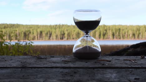 Zeitglas-Auf-Der-Holzoberfläche-Mit-Naturhintergrund