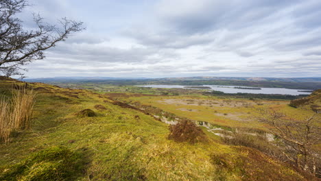 panorama motion timelapse of rural nature farmland with trees in the foreground grass field and hills and lake in distance during cloudy day viewed from carrowkeel in county sligo in ireland