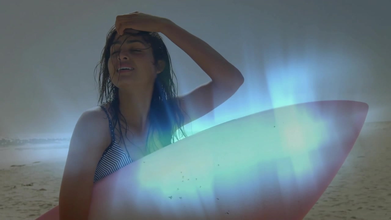 Surf su una spiaggia soleggiata, surfista donna che afferra una tavola da surf rosa, capelli gocciolanti mentre un bagliore blu si ritira.