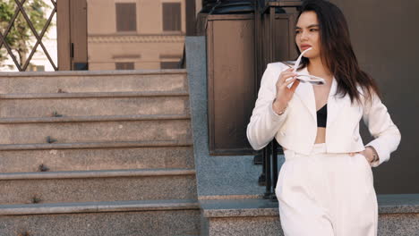 mujer elegante en traje blanco en las escaleras de la ciudad