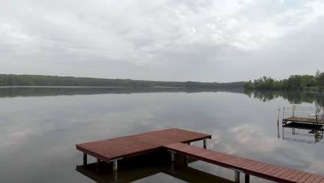 aerial: flying through trees on lovely european lake with empty pier