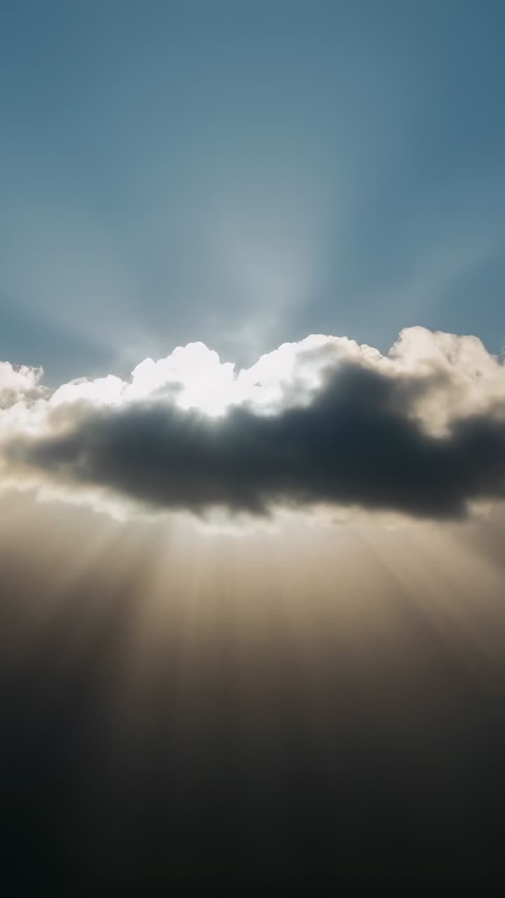 Video verticale: rendering di una densa nuvola singola che proietta raggi di sole verso il basso da una prospettiva dal basso, con il sole che fa capolino