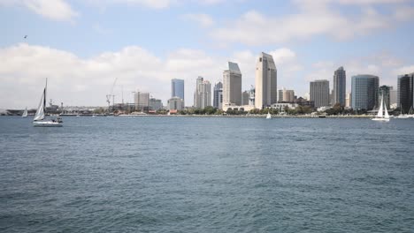 Boats-pass-by-in-the-ocean-with-the-city-of-San-Diego,-California-in-the-background