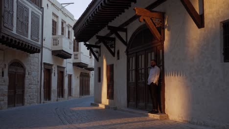 businessman standing next to the entrance of a renovated traditional building in the historic district of al seef in dubai, enjoying the warm light of the sunrise