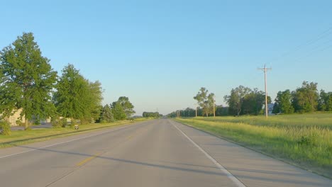 POV-while-driving-on-a-country-highway-past-farms-and-fields