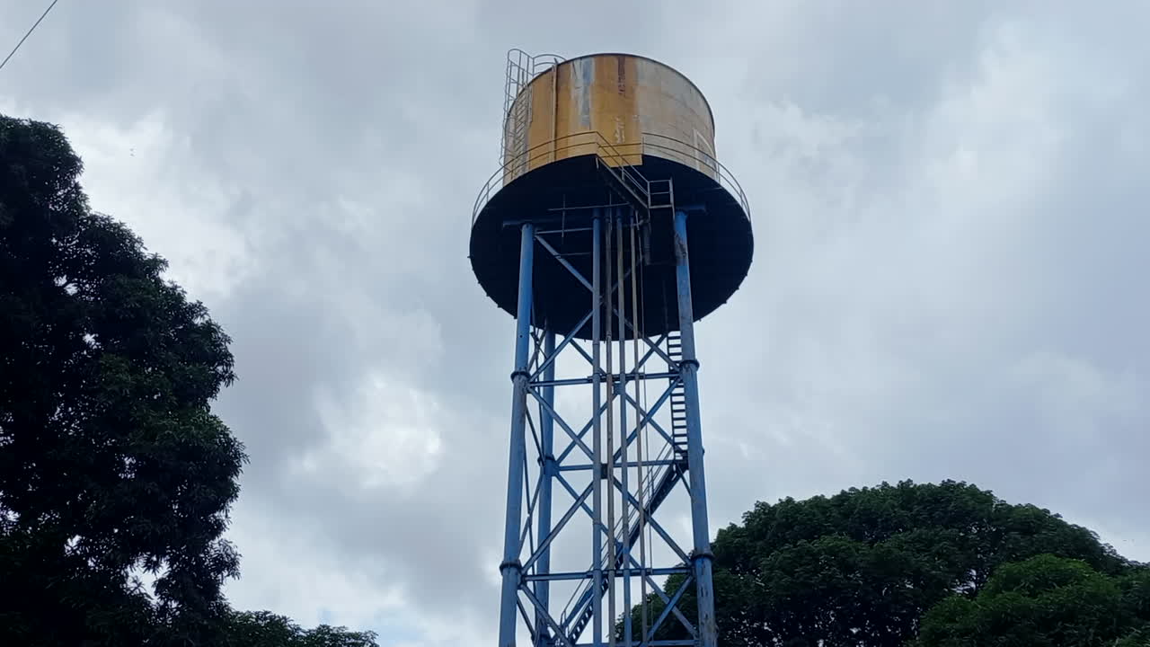 un gran tanque de suministro de agua, con árboles a su alrededor y un cielo gris, en el hospital de bissau