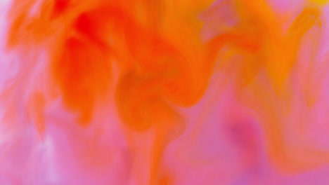 pink and orange paint or dye dropped into water against white background to create swirling colourful smoke background