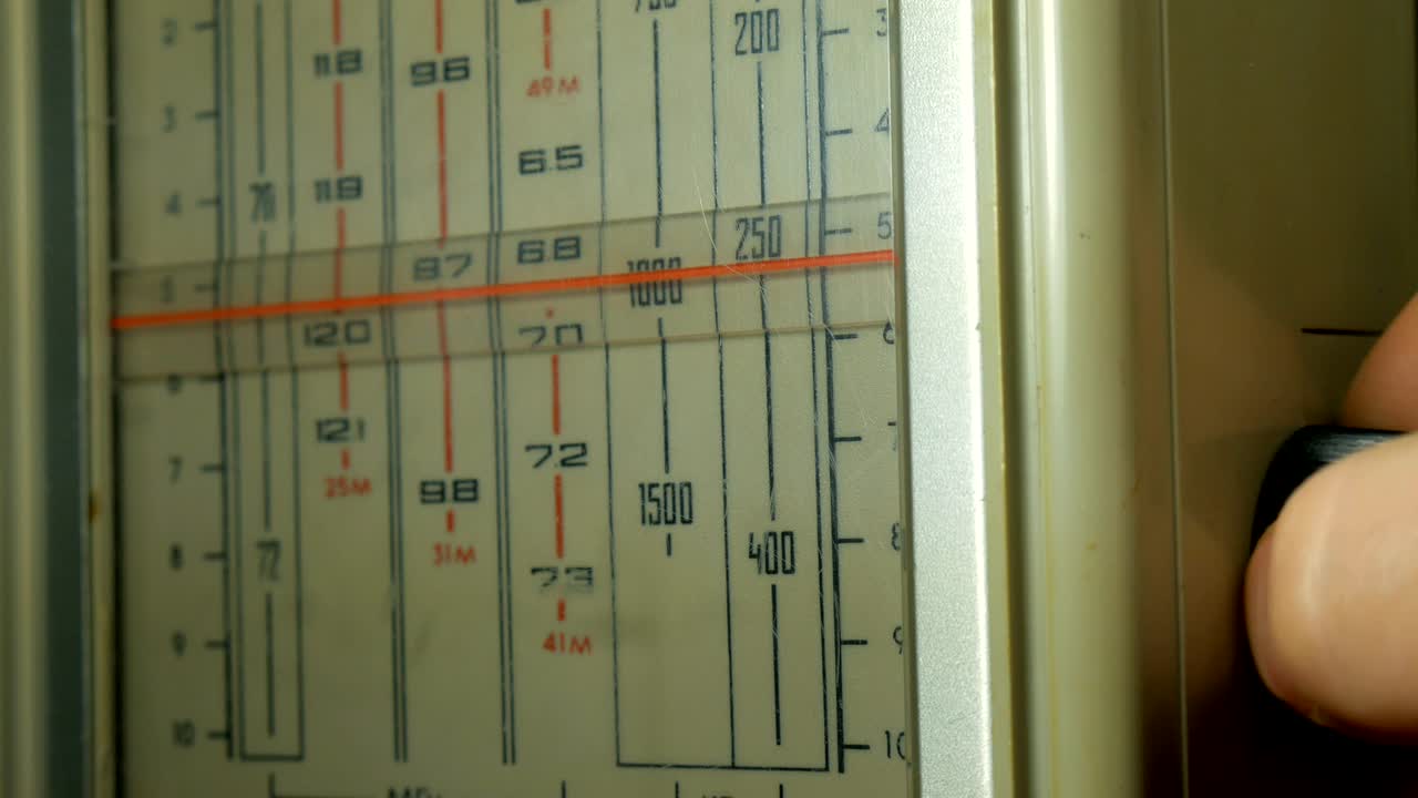 손으로 빈티지 라디오를 튜닝하는 남자. 남자들은 소리를 치고 있다. 오래된 라디오 다이얼