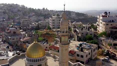aerial view of a mosque with a golden dome and minaret in a middle eastern town