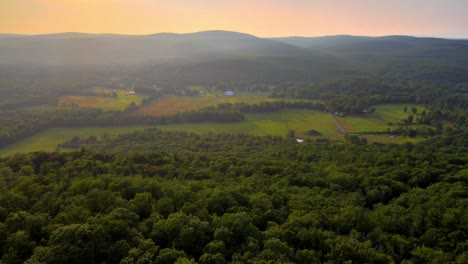 aerial drone video footage of a golden hour summer sunset in a green, vibrant rural appalachian mountain valley with beautiful light. in particular, this is in new york's hudson valley