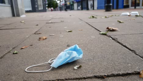 Basura-De-La-Máscara-Facial-Del-Virus-De-La-Corona-En-El-Suelo-En-Una-Calle-Tranquila-De-La-Ciudad