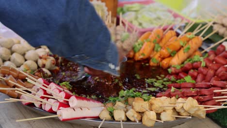 pouring sauce over assorted grilled skewers