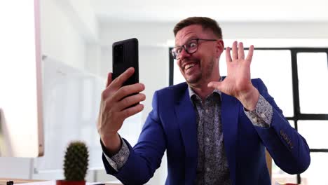 man making funny faces and waving during a video call in an office