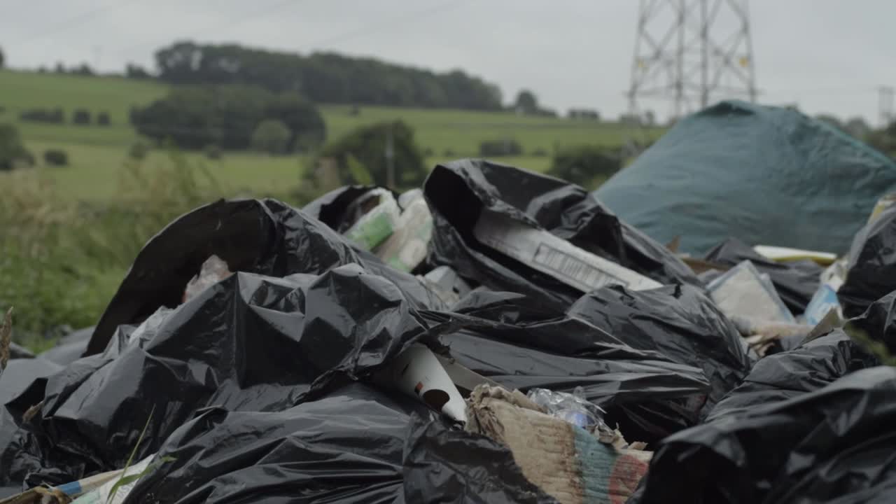Illegal waste and garbage dumped in countryside close up tilting shot
