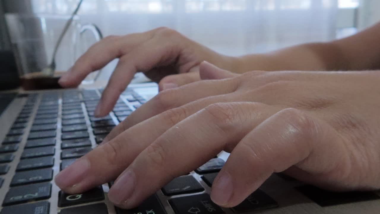Detailed front view close-up of hands on a laptop keyboard, fingers pressing keys