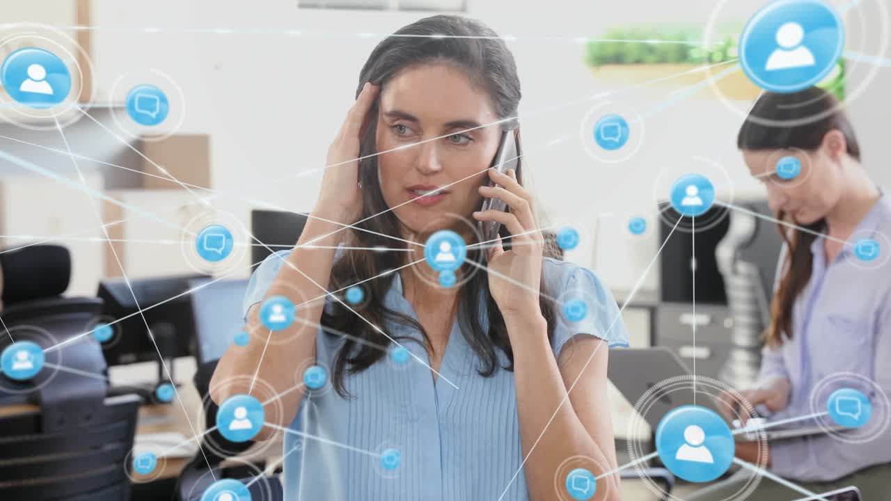 Animation of connected icons over confused caucasian woman talking on smartphone in office