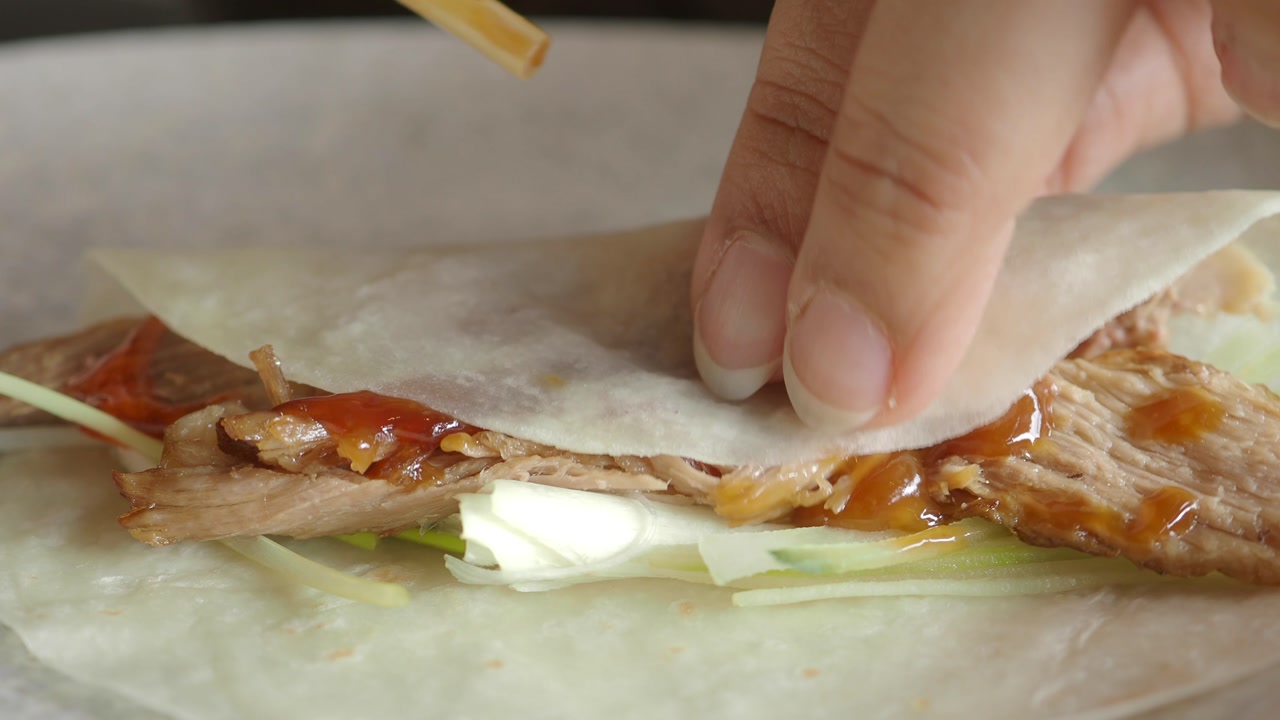 Close-up of Rolling a Peking Duck Wrap with Sauce