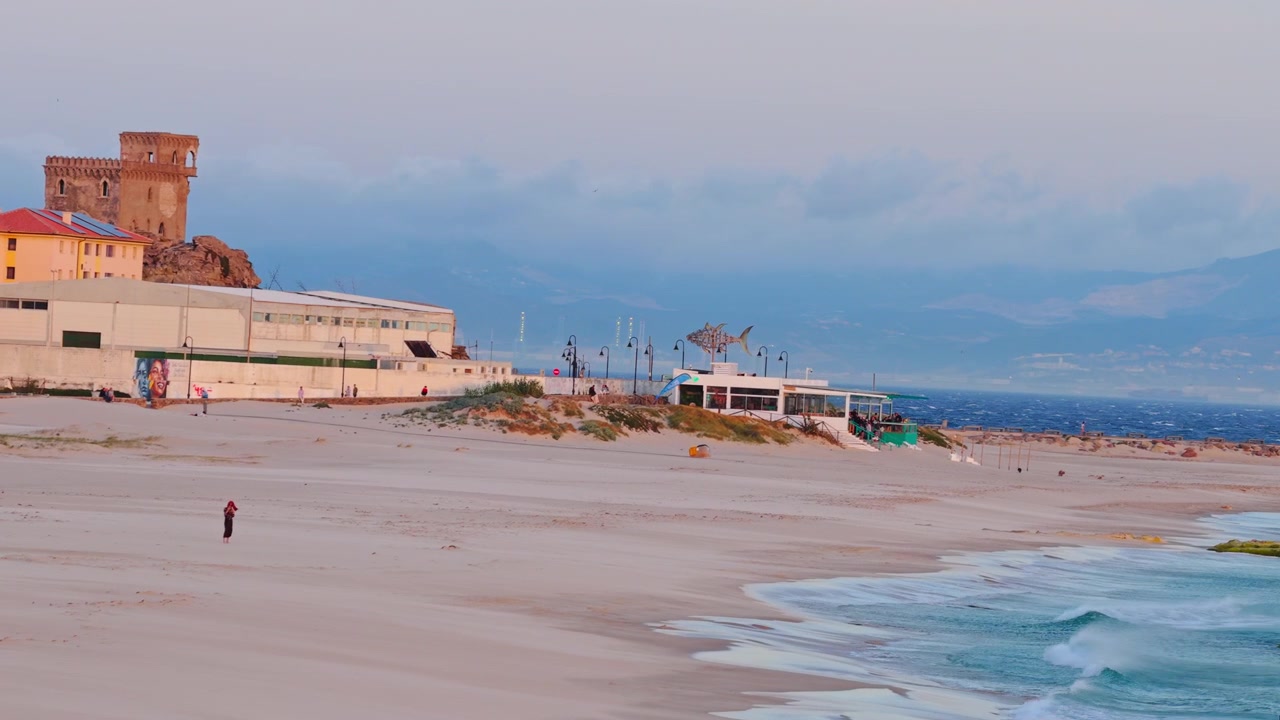 Toma cinematográfica con dron sobre la Playa de Los Lances en Tarifa, España. Amplias vistas aéreas revelan Balneario, la ciudad de Tarifa y las montañas de Marruecos al otro lado del Estrecho de Gibraltar.