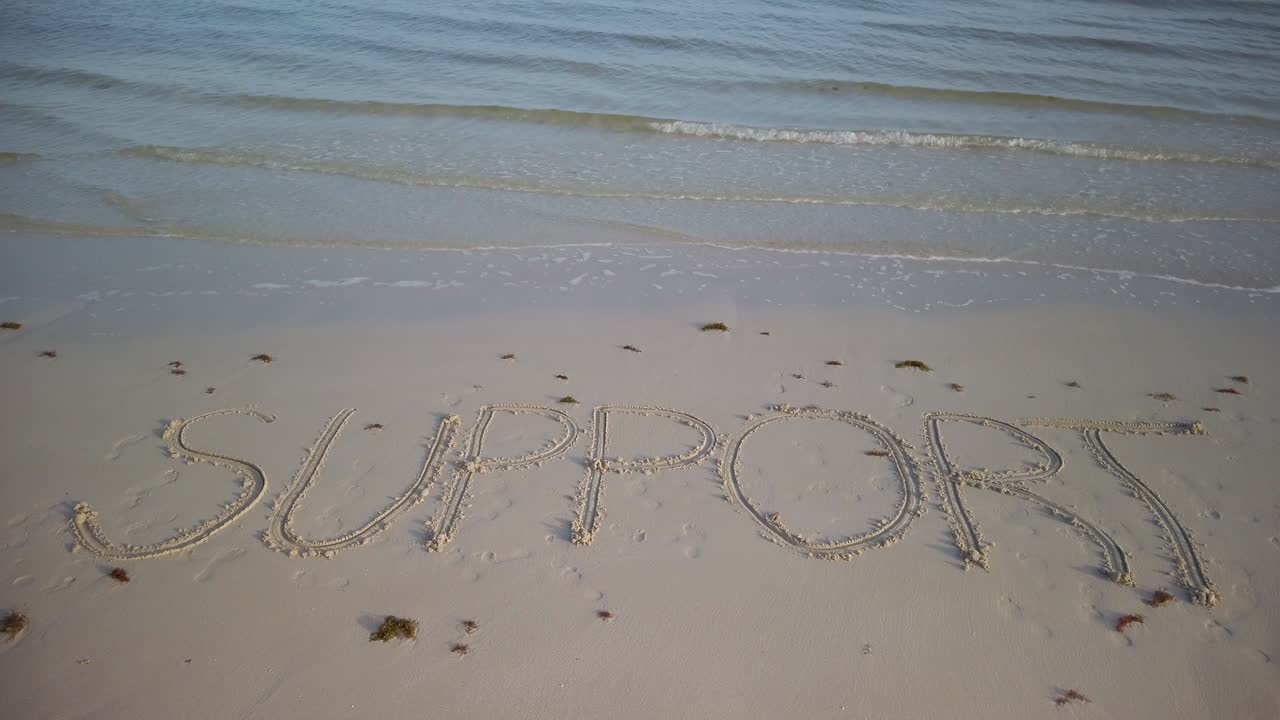 모래 위에 물이 찰싹 달라붙는 해변의 모래에 쓰여진 정적 지지 샷