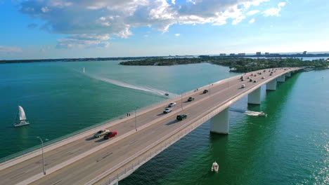 following vehicle traffic over a water bridge in a tropical setting while boats pass underneath bridge