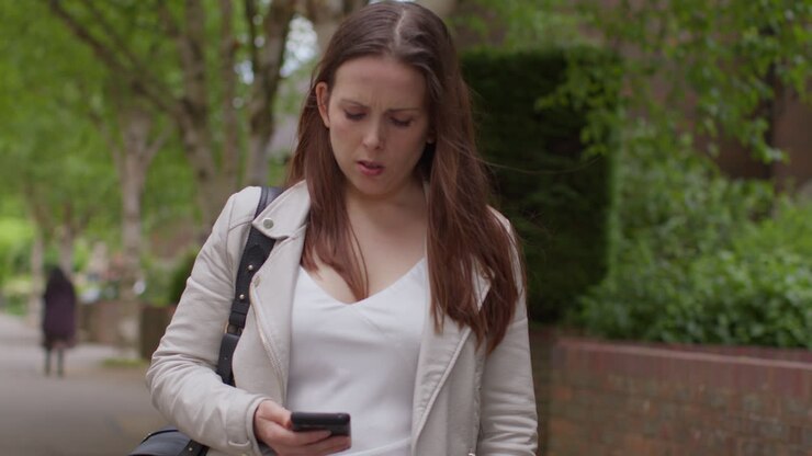 Donna stressata e ansiosa all'aperto con preoccupazioni finanziarie per la crisi del costo della vita, che controlla il portafoglio dopo aver guardato il telefono cellulare per strada in città