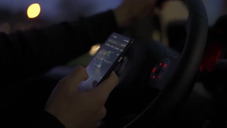 Unrecognizable-man-looking-on-map-on-his-mobile-phone-during-driving-at-night