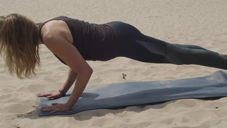 Bella-Mujer-Haciendo-Tablones-Y-Pose-De-Yoga-Para-Perros-Mirando-Hacia-Arriba-En-Dunas-De-Arena