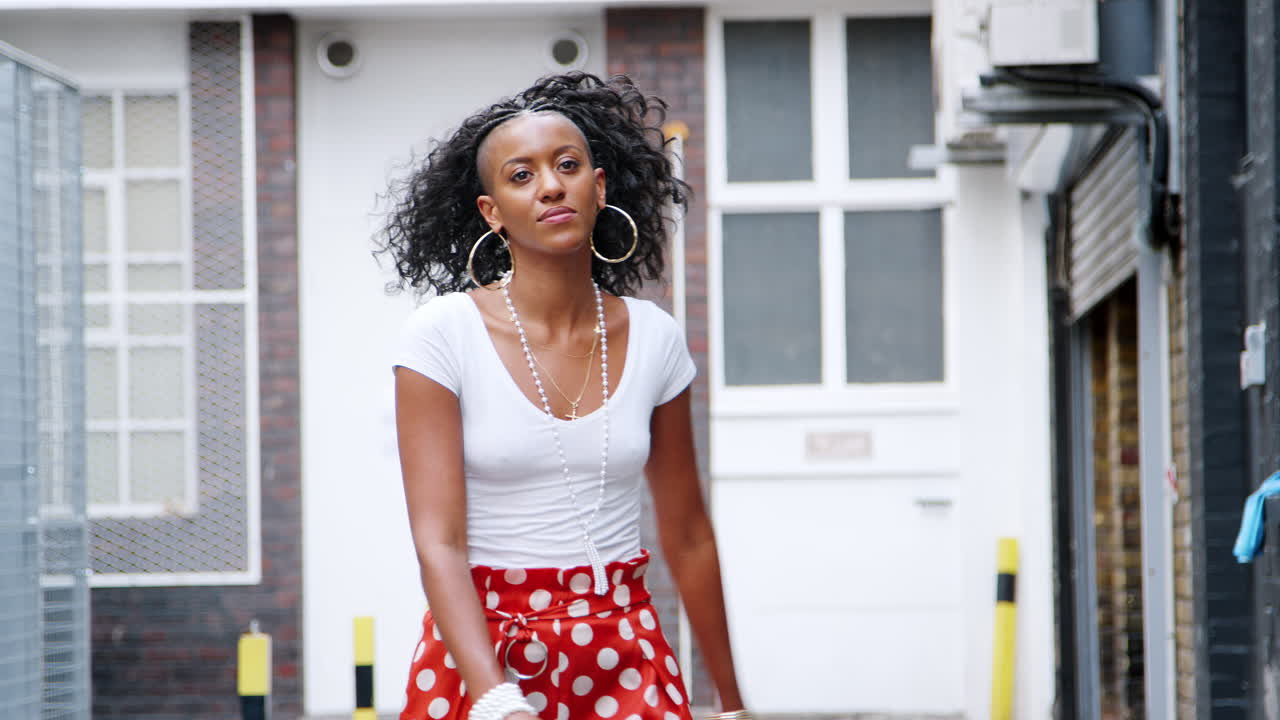 Fashionable young black woman wearing red polka dot trousers dancing in the street
