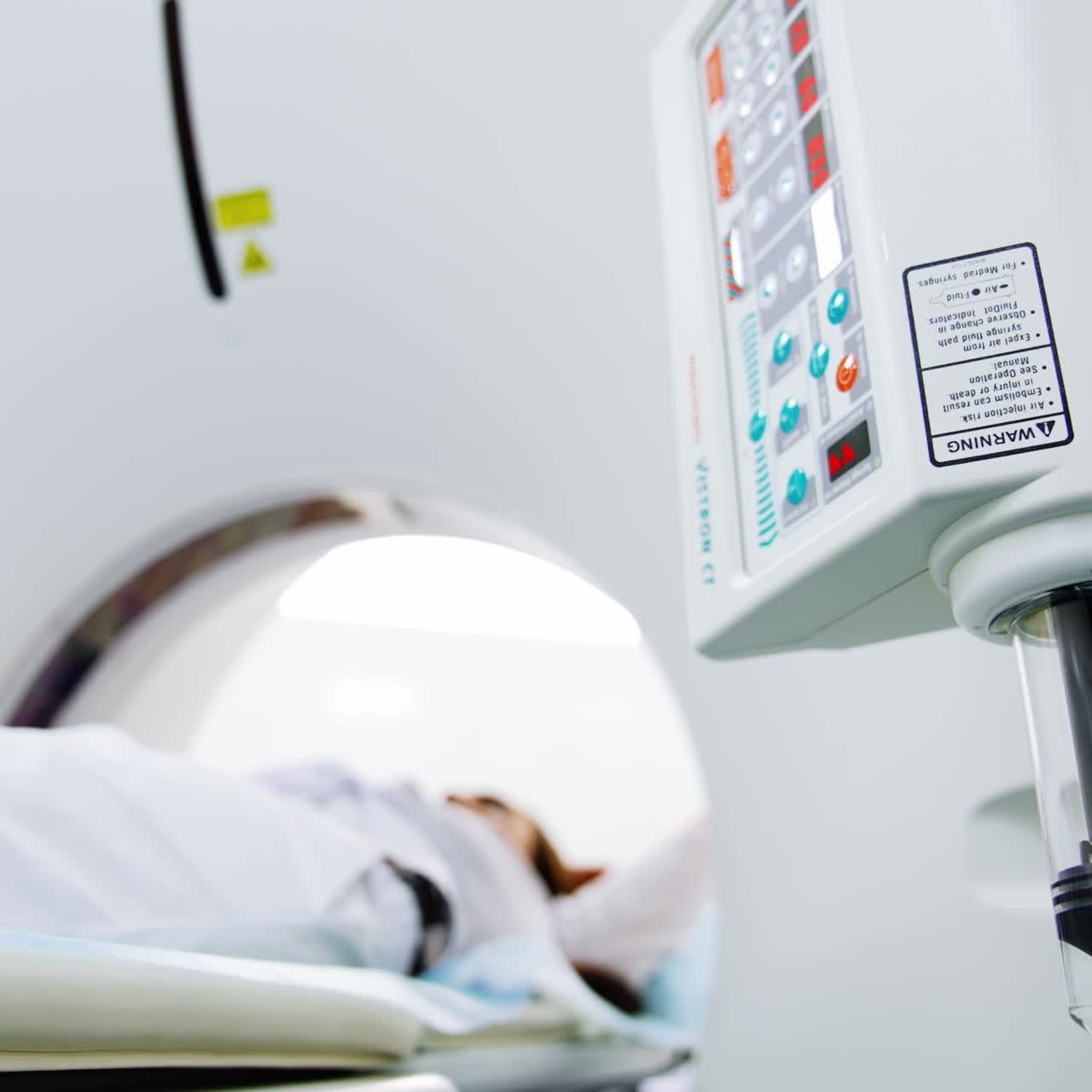 Il pistone nero nel serbatoio di vetro dell'apparecchiatura scende lentamente. È iniziata la procedura di scansione MRI. Il paziente è disteso sul lettino della macchina per tomografia computerizzata. Angolazione dal basso