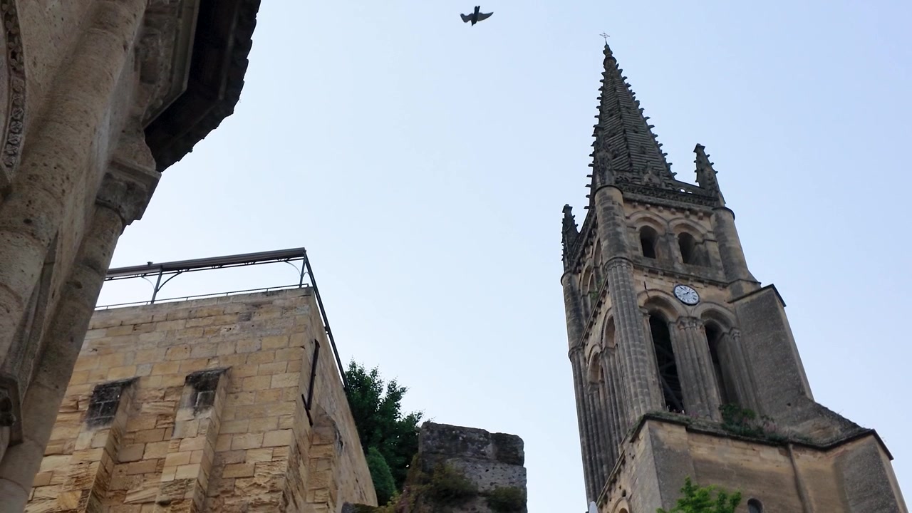 Vista dal basso di un campanile di chiesa storico in pietra contro un cielo azzurro e limpido.