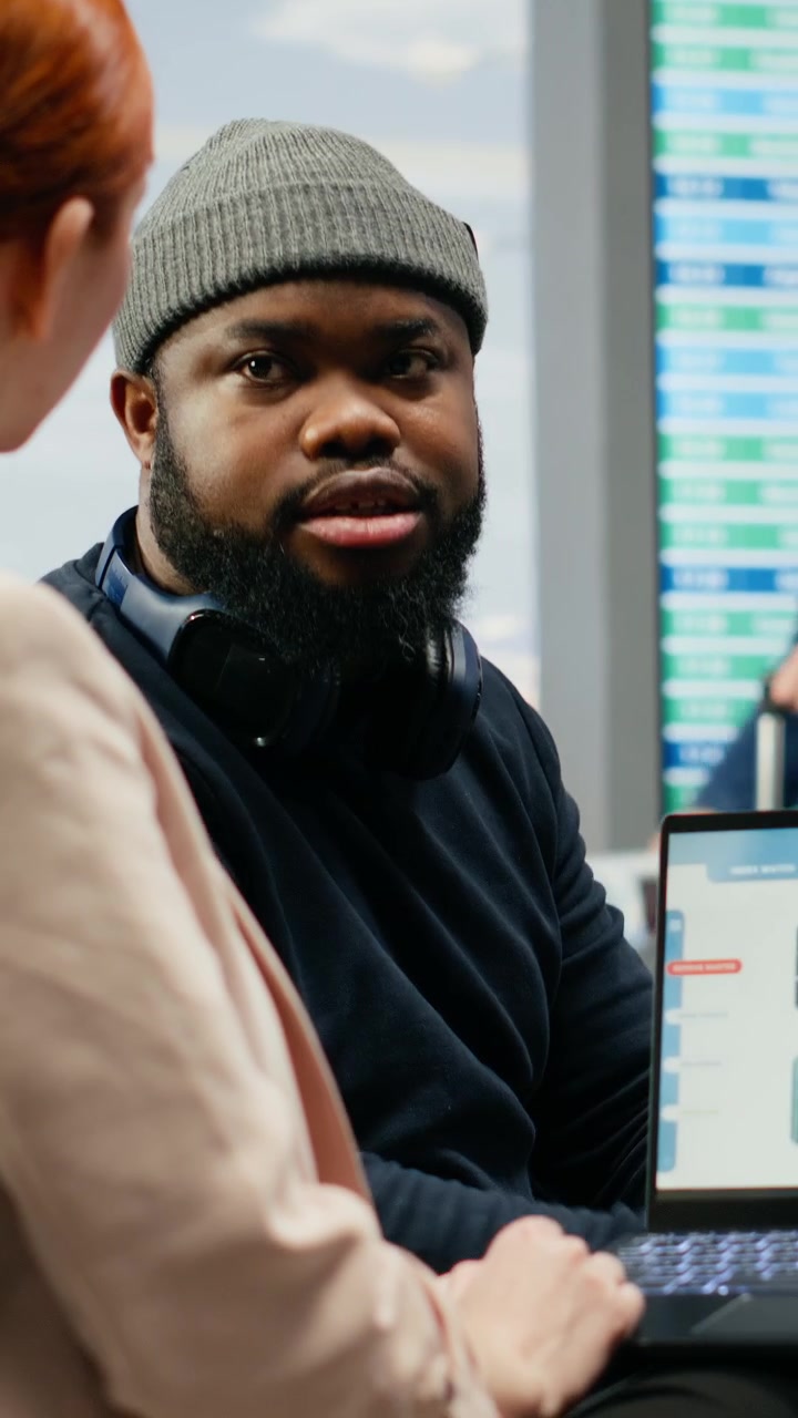 Vertikal video: Virksomhedsdirektør og assistent evaluerer virksomhedsdata og KPI'er i lufthavnslounge