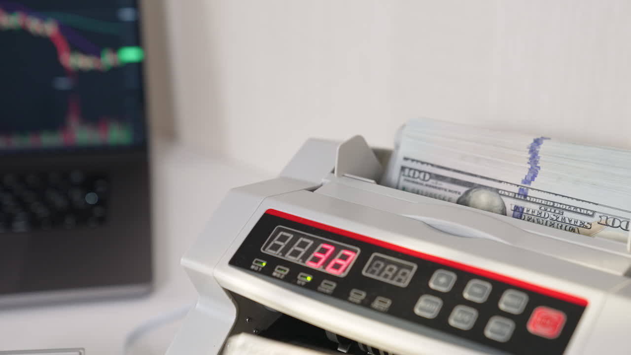 Placing hundred dollar wad into a cash machine slot. US currency disappearing quickly in the equipment. Close up.