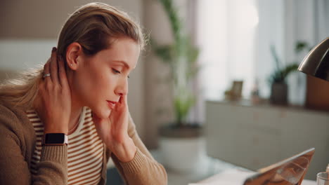 woman with blonde hair looking worried while using tablet