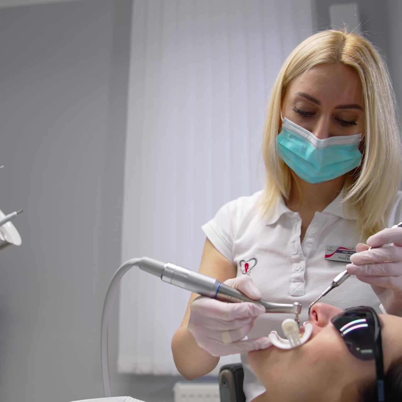 Professional dentist doctor repairing patient tooth. Young stomatology worker in modern hospital