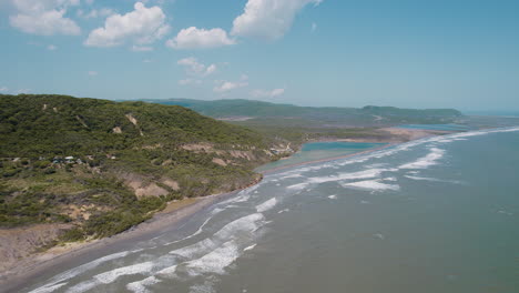 Aerial-serenity-in-Puerto-Colombia:-Small-waves-gracefully-crash-upon-the-tranquil-beach,-creating-a-soothing-and-picturesque-coastal-panorama