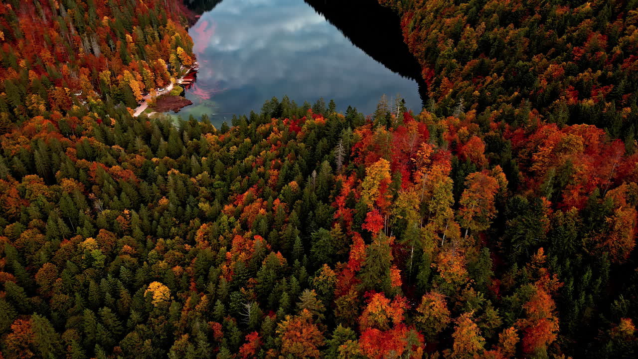 Aerial drone shot flying high over Lake Toplitz in mountain valley, surrounded by autumnal forests in Austria on a cloudy day