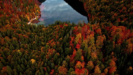 Aerial-drone-shot-flying-high-over-Lake-Toplitz-in-mountain-valley,-surrounded-by-autumnal-forests-in-Austria-on-a-cloudy-day